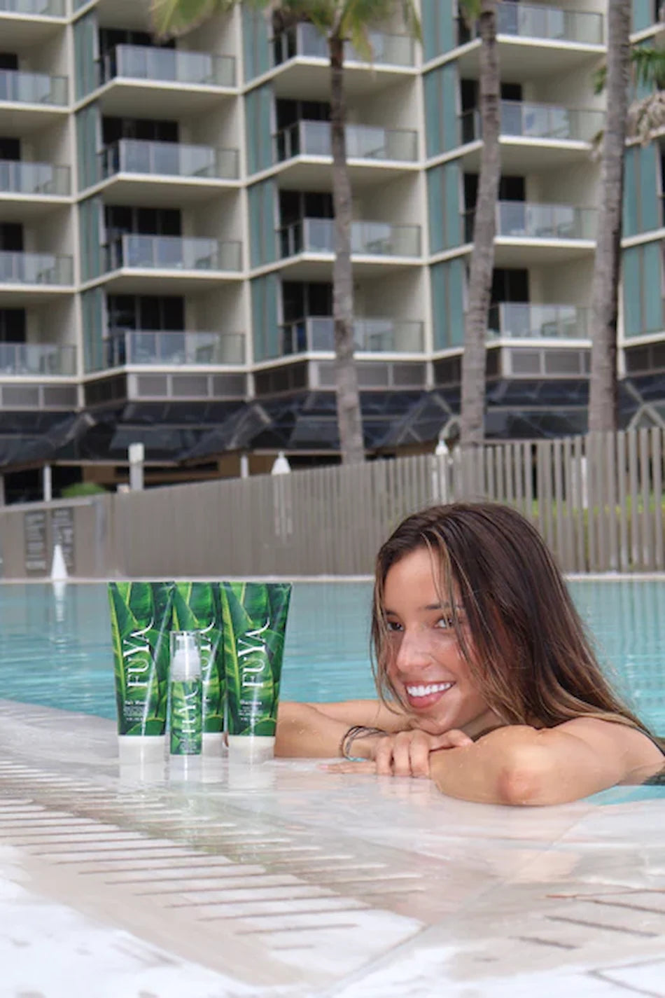 FUYA Haircare poolside collection – woman relaxing by the pool with FUYA Repair & Shine products in foreground
