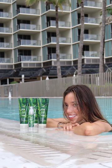 FUYA Haircare poolside collection – woman relaxing by the pool with FUYA Repair & Shine products in foreground